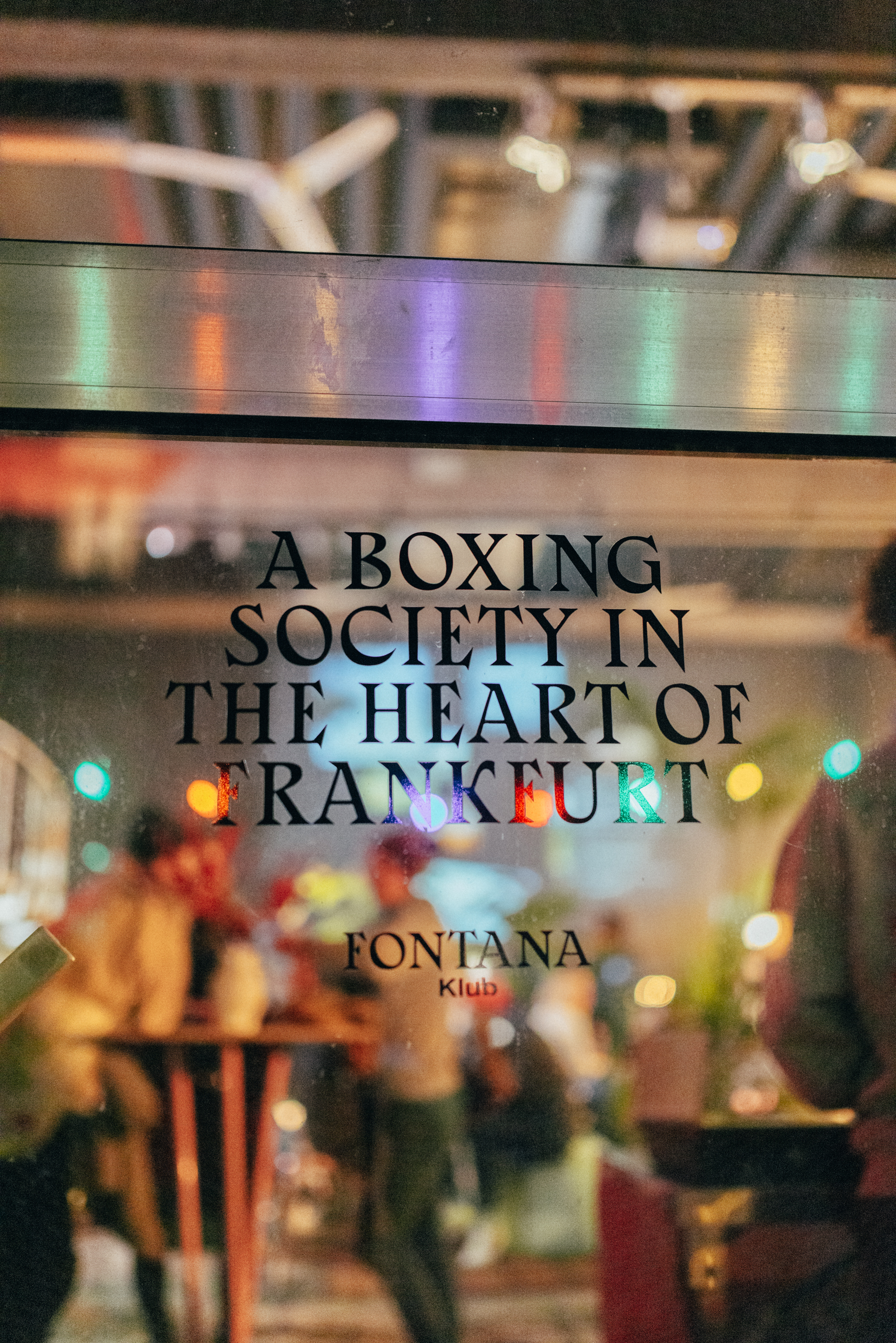 Blick in die Halle durchs Tor-Fenster, auf dem »A BOXING SOCIETY IN THE HEART OF FRANKFURT – Fontana Klub« steht.